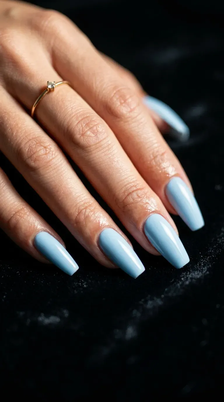 Close-up of manicured hand with light blue polish on coffin-shaped nails