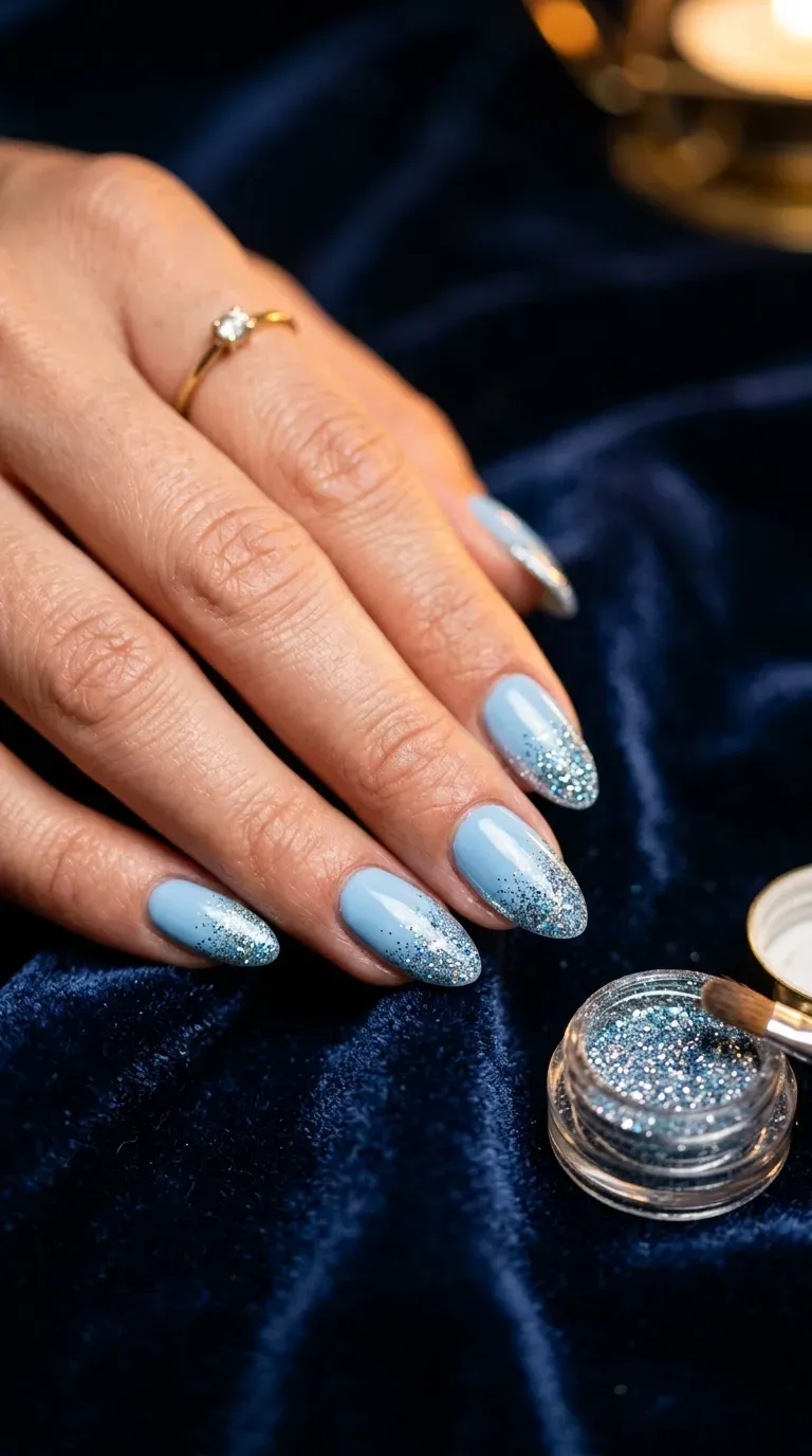 Close-up of manicured hand with light blue nails featuring glitter tips