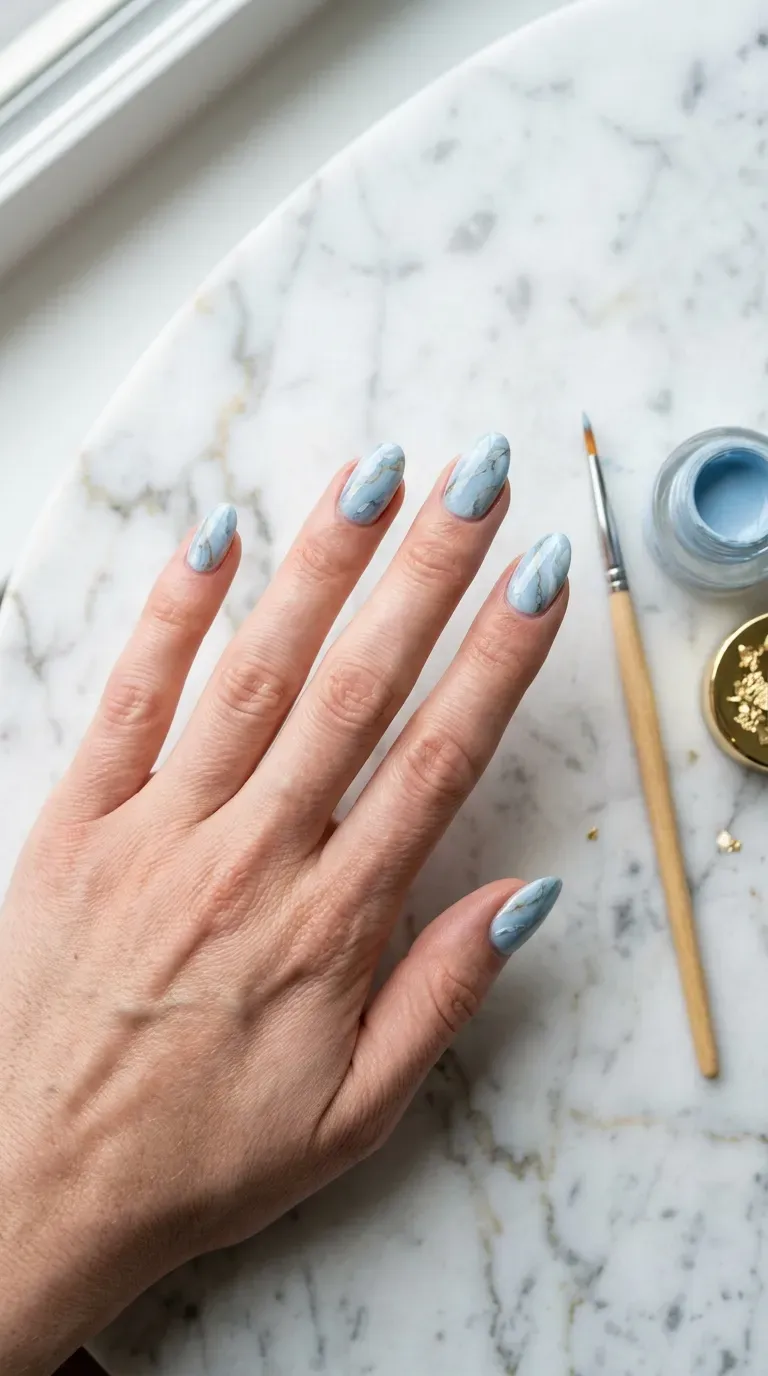 Close-up of manicured hand with light blue marble-effect nail design