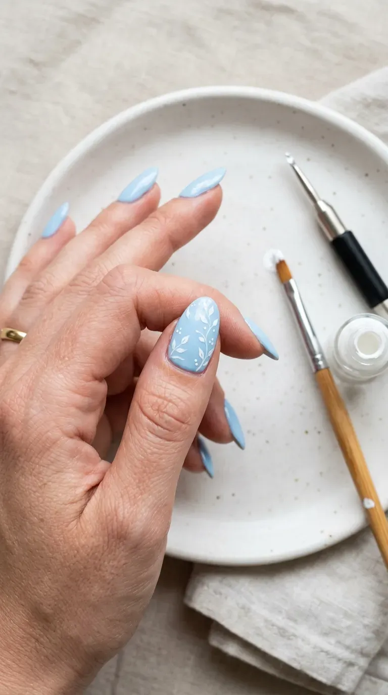 Close-up of manicured hand with light blue nails featuring small white accent details