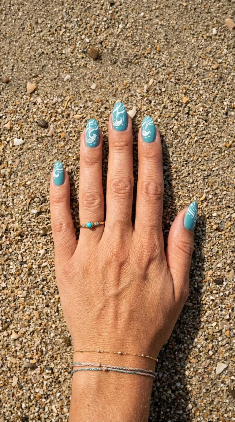 Close-up of manicured hand with mermaid-themed nails featuring hand-painted wave designs